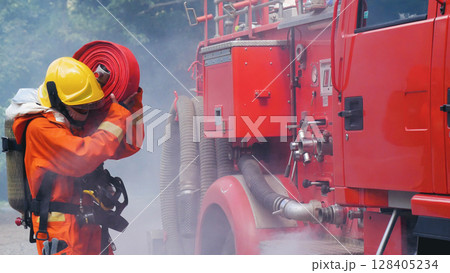 Fireman prepare equipment at fire engine truck. Man hand connect water tube with fire truck fighting extinguisher. Firefighter using fire hose, tube, chemical water foam spray police rescue training 128405234
