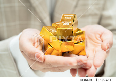 Asian woman holding gold bar in finance business. Asian woman holding gold bar in finance business. 128405241