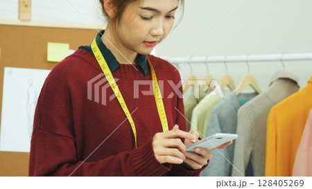 Entrepreneur fashion designer in textile business designing new retail clothing collection. Happy working woman seamstress, designer working on fabric sketches. Young designer fashion concept Entrepreneur fashion designer in textile business designing new retail clothing collection. Happy working woman seamstress, designer working on fabric sketches. Young designer fashion concept 128405269