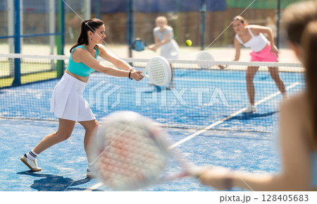 Woman playing with other paddle tennis players 128405683