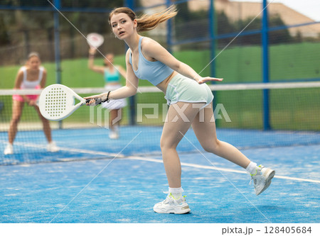 Woman standing on court and playing paddle tennis Woman standing on court and playing paddle tennis 128405684