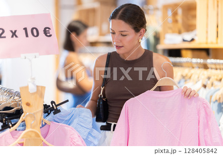 Young woman choosing blouse in clothing store 128405842