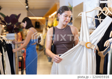 Young woman choosing dress in clothing store Young woman choosing dress in clothing store 128405916