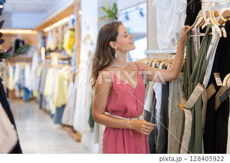 Young woman choosing dress in clothing store Young woman choosing dress in clothing store 128405922
