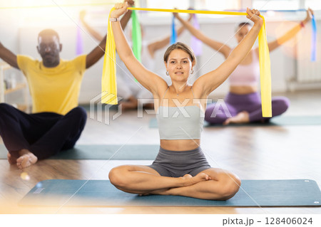 Girl exercising with elastic band during group fitness class Girl exercising with elastic band during group fitness class 128406024
