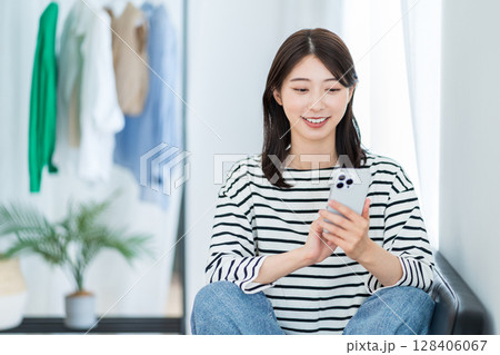 リビングでスマホを使う若い女性 リビングでスマホを使う若い女性 128406067
