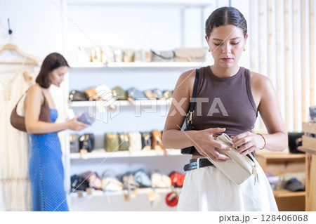Girl customer chooses lady bag in store Girl customer chooses lady bag in store 128406068