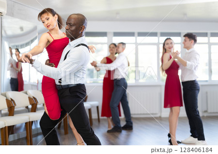 Woman dances incendiary boogie woogie with African man partner during choreography lesson 128406184
