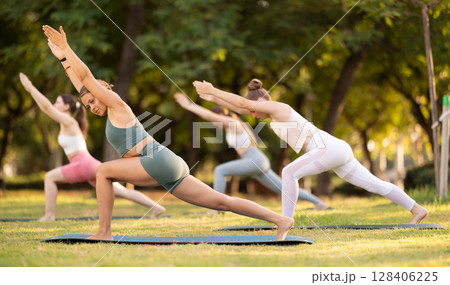 Yoga lesson visitors girls perform Utthita Parshvakonasana in park 128406225