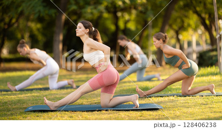 Yoga lesson visitors girls perform Ardha Parshvottanasana in park Yoga lesson visitors girls perform Ardha Parshvottanasana in park 128406238