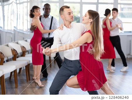 Happy woman enjoying impassioned merengue with male partner in dance room during party. Social dancing concept Happy woman enjoying impassioned merengue with male partner in dance room during party. Social dancing concept 128406240