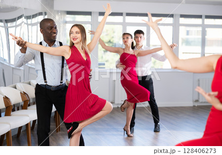 African American practicing bachata with brunette in red in dance class African American practicing bachata with brunette in red in dance class 128406273