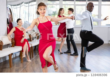 Woman dances incendiary boogie woogie with African man partner during choreography lesson Woman dances incendiary boogie woogie with African man partner during choreography lesson 128406306