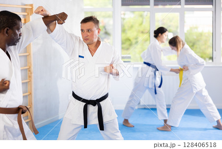 Two men practicing punches during karate classes in gym Two men practicing punches during karate classes in gym 128406518