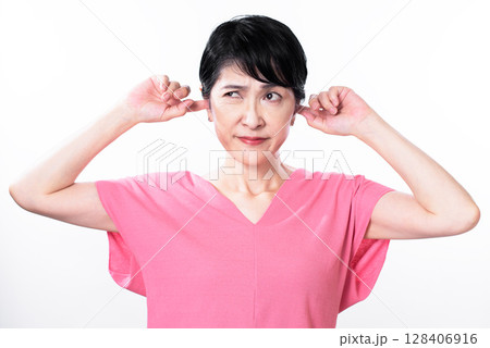 耳をふさぐピンク色のサマーニットを着た中年女性 128406916