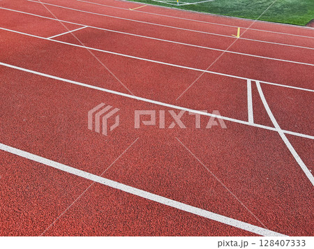 Empty red running track with white lines suggesting movement. 128407333