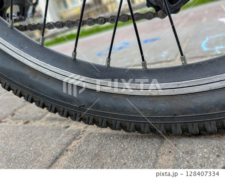 Close-up of a bicycle wheel on a pavement. Close-up of a bicycle wheel on a pavement. 128407334