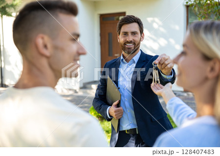 A cute young couple getting keys from the real estate agent and looking excited 128407483