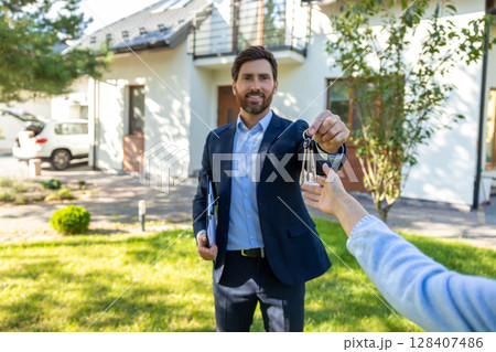 Real state agent giving the key from a new house to the clients Real state agent giving the key from a new house to the clients 128407486