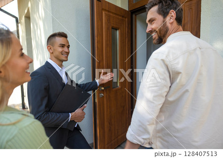 Agent inviting clients to tour new home in suburban setting 128407513