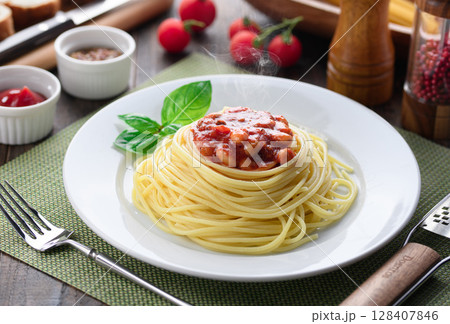 湯気立つチリコンカンパスタと彩り豊かな洋食テーブル 128407846