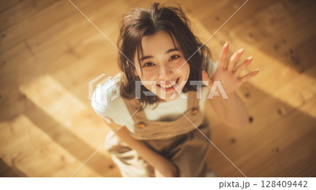 俯瞰で見る明るく手を振る笑顔の若い女性｜笑顔, 俯瞰, 挨拶	 128409442