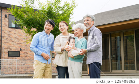 住宅の前で笑顔で赤ちゃんを囲む三世代家族 住宅の前で笑顔で赤ちゃんを囲む三世代家族 128409862