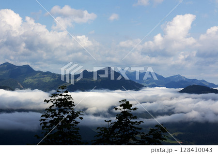 Breathtaking view of Tyrol mountains shrouded in mist revealing lush valleys and rolling peaks during a cloudy day 128410043