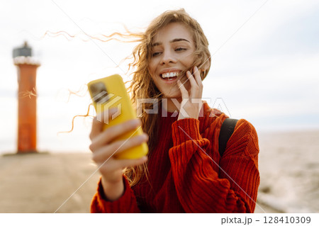 Young woman enjoying nature by the waterfront during a cloudy day by a lighthouse. Blogging concept Young woman enjoying nature by the waterfront during a cloudy day by a lighthouse. Blogging concept 128410309