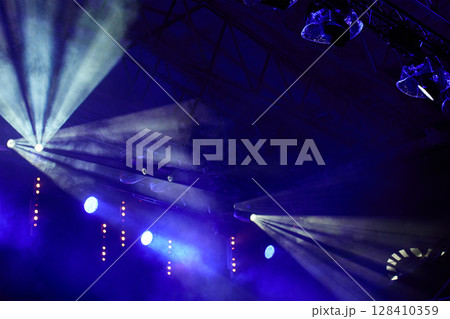 Stage with bright concert lighting, spotlights and smoke effects prepared for live music performance. Illumination for music event 128410359