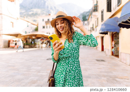 Pretty woman walks the streets with mobile phone. Tourist using mobile app searching way. 128410660
