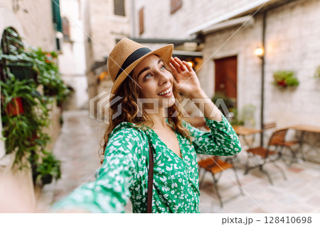Beautiful woman walks the streets and takes selfie using smartphone camera 128410698