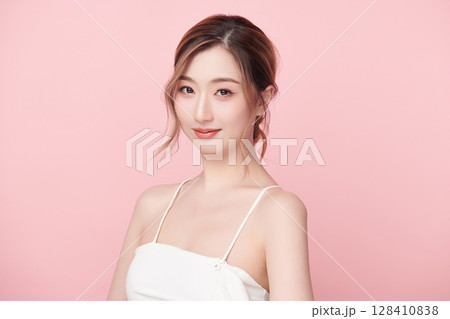 A beautiful young Asian woman with clean, fresh skin against a pink background. Skincare, facial treatment, cosmetology, beauty, and spa. An elegant portrait of an Asian woman. 128410838