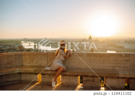 Portrait of happy woman tourist in hat at dawn enjoys cityscape. concept of an active lifestyle. Portrait of happy woman tourist in hat at dawn enjoys cityscape. concept of an active lifestyle. 128411102
