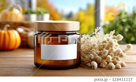An amber glass jar with a blank label sits on a table, surrounded by autumn decor, creating a cozy, welcoming vibe 128411117