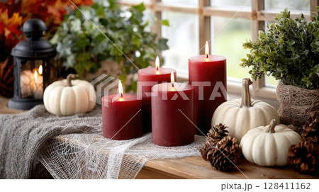 Dark red candles glow on a gothic table adorned with pumpkins, spider webs, and vampire-themed decorations for Halloween festivities Dark red candles glow on a gothic table adorned with pumpkins, spider webs, and vampire-themed decorations for Halloween festivities 128411162