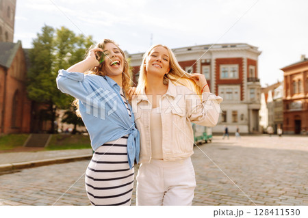 Female tourists in bright dress enjoys sights of city on sunny day. Concept of lifestyle, fashion. Female tourists in bright dress enjoys sights of city on sunny day. Concept of lifestyle, fashion. 128411530