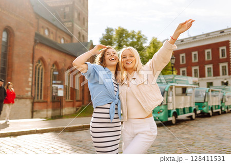 Female tourists in bright dress enjoys sights of city on sunny day. Concept of lifestyle, fashion. Female tourists in bright dress enjoys sights of city on sunny day. Concept of lifestyle, fashion. 128411531