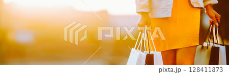 Young woman with shopping bags walking on street. Female coming from a sale downtown 128411873