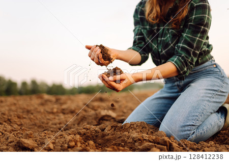 Close-up of woman farmer's hands with black soil in agricultural field. Ecology, gardening concept. 128412238