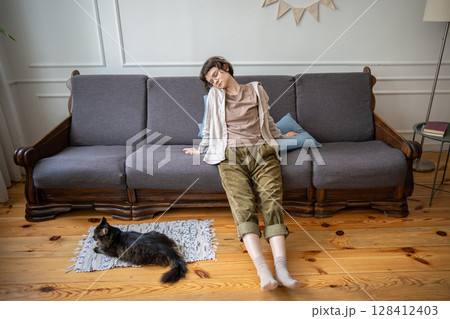 Weary apathetic woman lying still in relaxed pose while cat lying on floor, boredom and laziness Weary apathetic woman lying still in relaxed pose while cat lying on floor, boredom and laziness 128412403