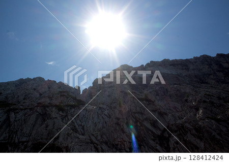 Sun shining over rugged cliffs 128412424