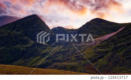 Peaceful highland scene at sunset. The mountains stand tall under a vibrant, colorful sky. Nature's beauty captured. Peaceful highland scene at sunset. The mountains stand tall under a vibrant, colorful sky. Nature's beauty captured. 128413717