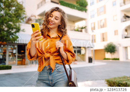 Young woman walking down street and using mobile phone. Business, technology, blogging concept. Young woman walking down street and using mobile phone. Business, technology, blogging concept. 128413726