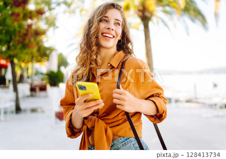 Young woman walking down street and using mobile phone. Business, technology, blogging concept. 128413734
