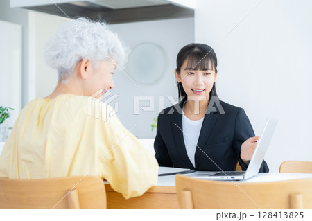 リビングでシニア女性と商談をするビジネスウーマン 128413825