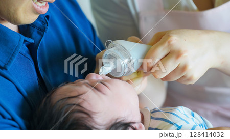 赤ちゃんに鼻水吸引器を使う両親 赤ちゃんに鼻水吸引器を使う両親 128414032