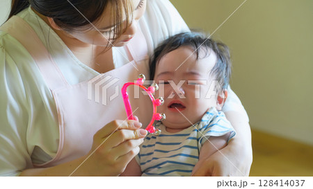 赤ちゃんを抱っこしてあやす女性 128414037