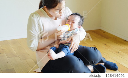 赤ちゃんに哺乳瓶でミルクを飲ませる女性 128414091