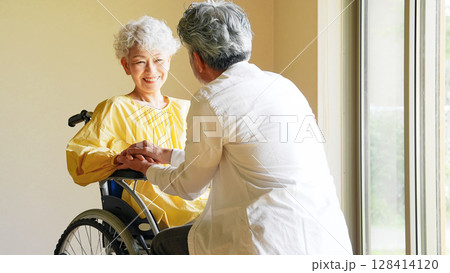 車椅子のシニア女性を介護するシニア男性 車椅子のシニア女性を介護するシニア男性 128414120